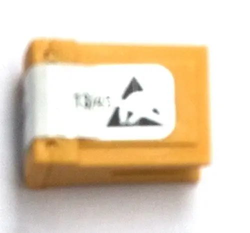 Gelbes elektronisches Bauteil mit grauem Aufkleber, das einen Recyclinghinweis zeigt. Möglicherweise ein Stecker von Daikin für Heizungsanlagen.